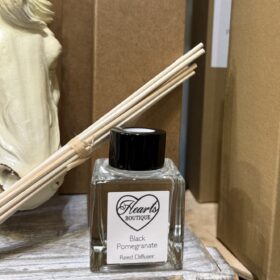 Our Black Pomegranate reed diffuser displayed on a shelf.