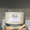 Our Lime Basil & Mandarin Candle on display on a rustic log.