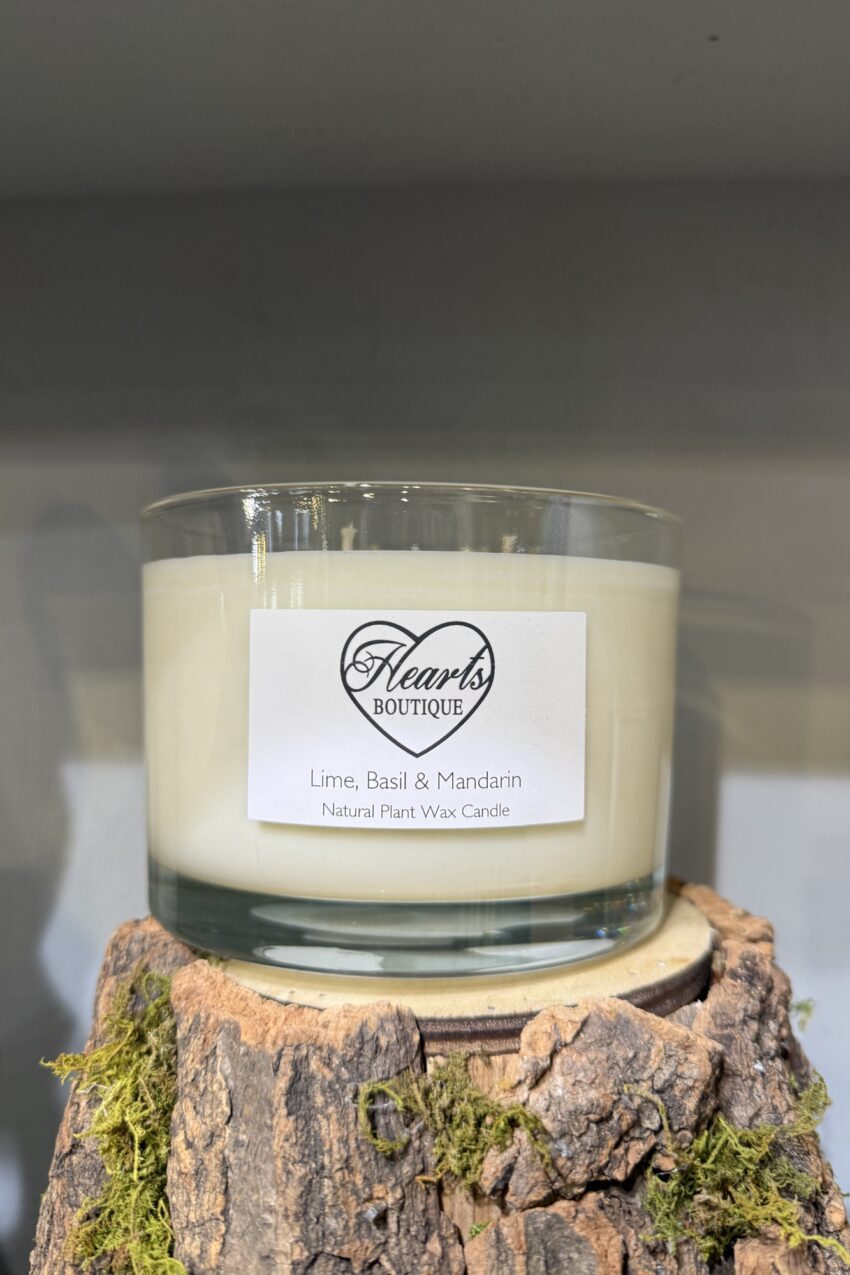 Our Lime Basil & Mandarin Candle on display on a rustic log.